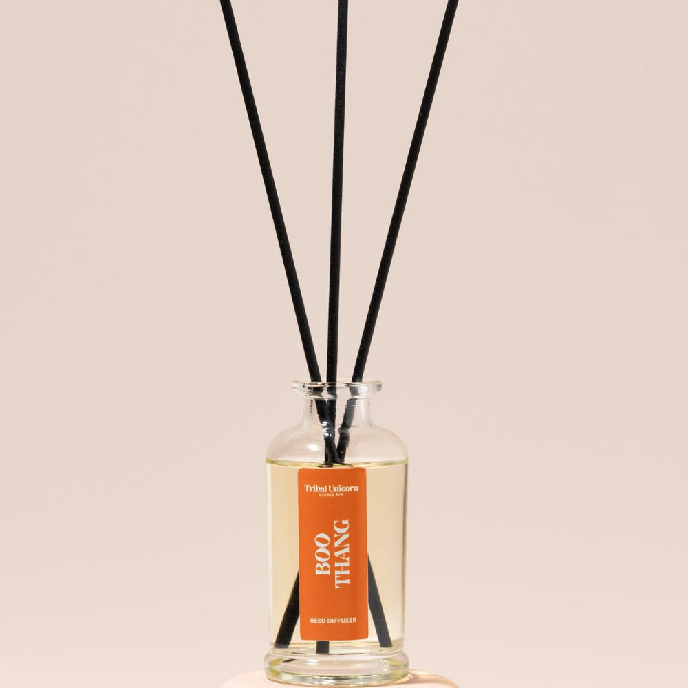 Reed diffuser with black sticks and a label on a beige background