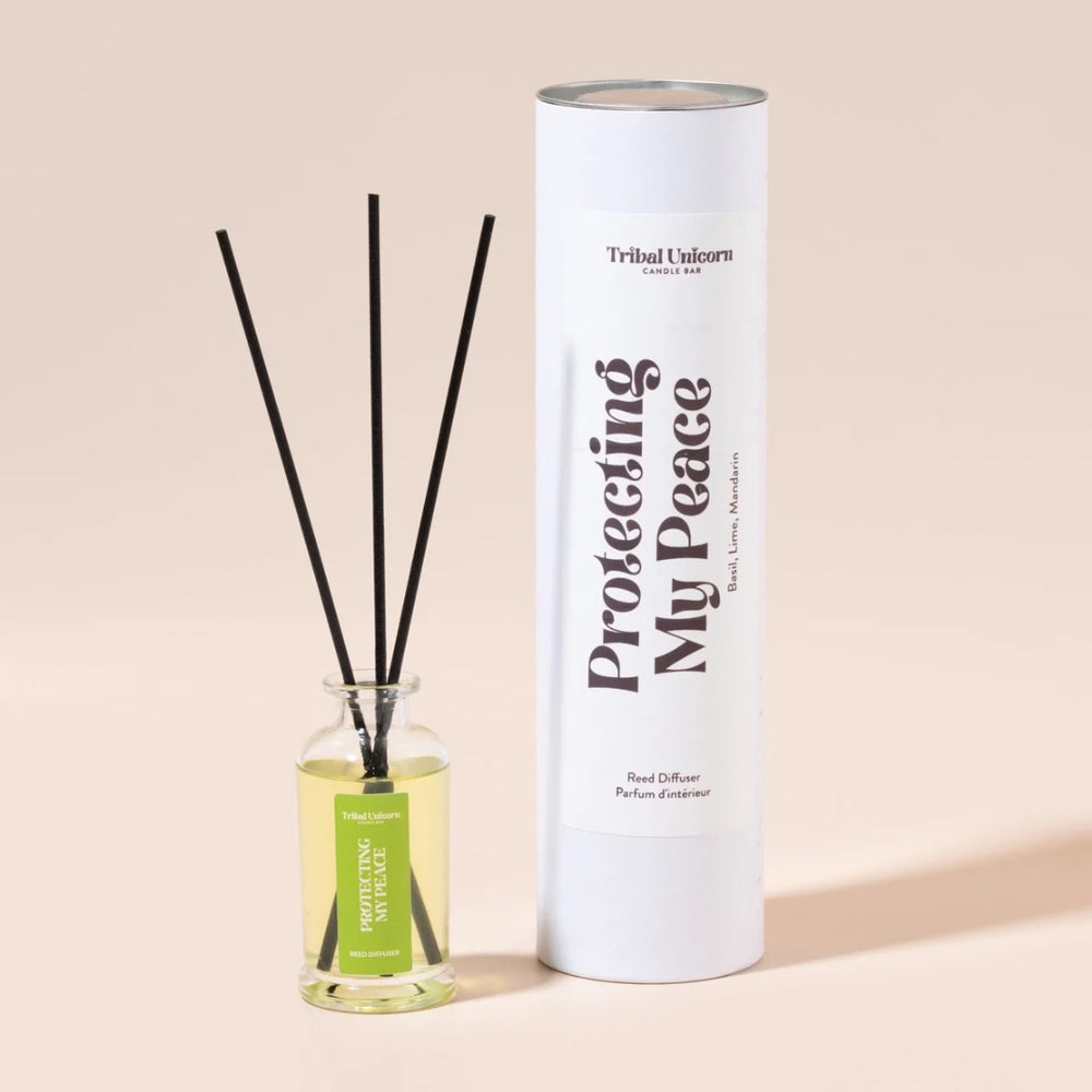 Reed diffuser with black sticks and a cylindrical container labeled 'Tribal Unicorn' on a beige background