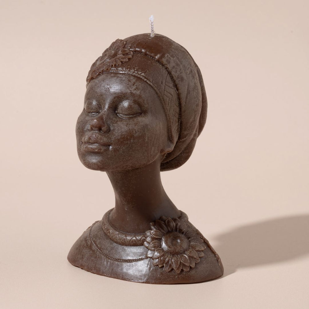 Candle in the shape of a woman's head with a turban on a beige background