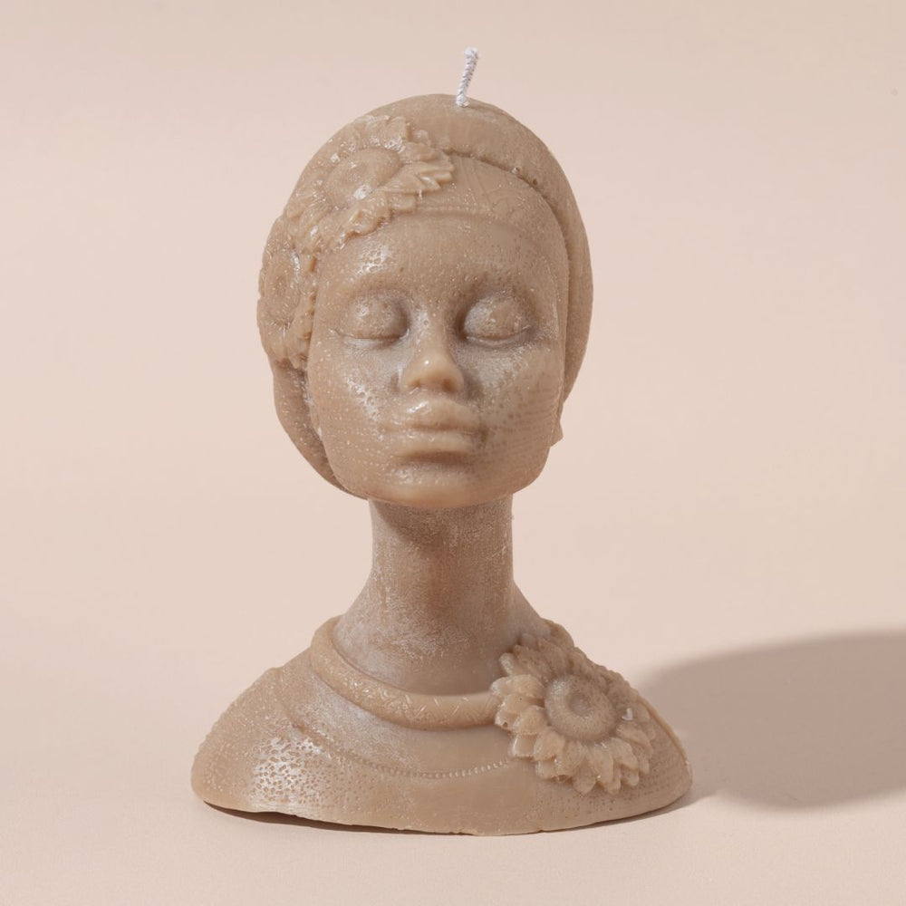 Candle shaped like a woman's head with flowers on a beige background